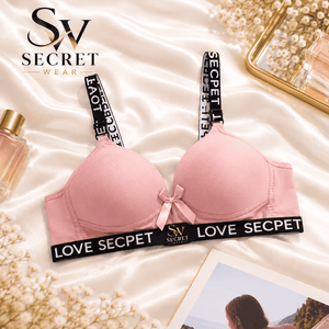 Love Secret Padded Bra in soft pink with smooth molded cups, black logo-print straps and band, and a satin bow.